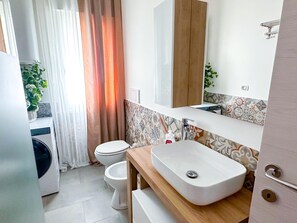 Ein modernes Badezimmer mit einem weißen Waschbecken, einer Toilette und einer Dusche.