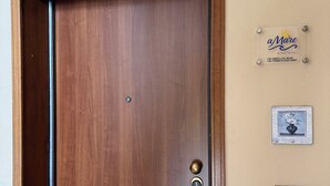 A wooden door with a brass handle and a keyhole, a wall-mounted sign with the name 'a Mare Apartment', and three framed pictures of vases on the wall. - aMare Apartment, cozy accommodation a few steps from the sea (Nettuno)
