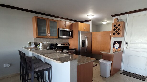 A modern kitchen with a central island, stainless steel appliances, and wooden cabinets. - Enjoy in Charming Place, 3-bedroom, 2 bathroom with AC in Río Grande (Río Grande)