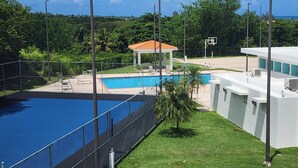 A swimming pool with a gazebo, a basketball hoop, and a modern building with air conditioning units. - Enjoy in Charming Place, 3-bedroom, 2 bathroom with AC in Río Grande (Río Grande)