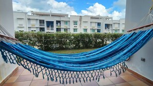 A blue hammock hanging between two walls in a residential area with a view of a multi-story building in the background. - Enjoy in Charming Place, 3-bedroom, 2 bathroom with AC in Río Grande (Río Grande)