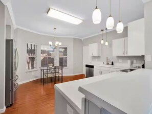 A modern kitchen with white cabinetry, a central island, and pendant lighting. - Frisco Castle 3BR Garage Parking Gated Backyard (Frisco)