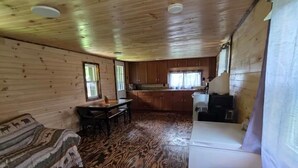 Ein gemütliches Blockhausschlafzimmer mit Holzboden, einer Couch, einem Esstisch und einer Küchenzeile.