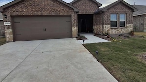 A two-story brick house with a garage and a stone facade.