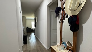 A hallway with a wooden bench, a mirror, and hats hanging on the wall.