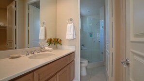 Ein Badezimmer mit großem Spiegel, zwei Waschbecken, einer Dusche und einer Toilette.