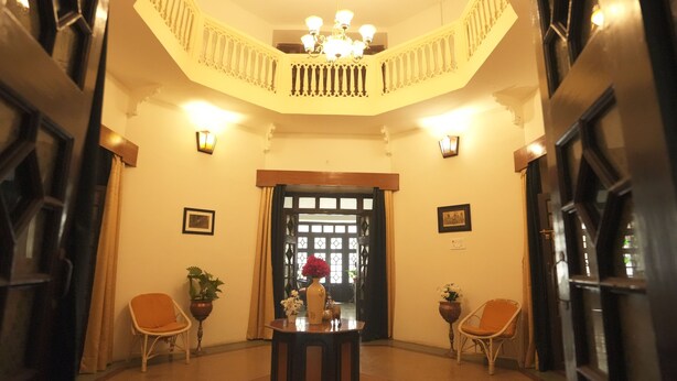Eine Lobby mit Treppe, zwei Stühlen, einem Tisch und einer Chandelüster.