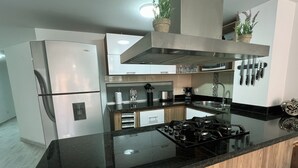 A modern kitchen with a stainless steel refrigerator, a gas stove, and wooden cabinets.
