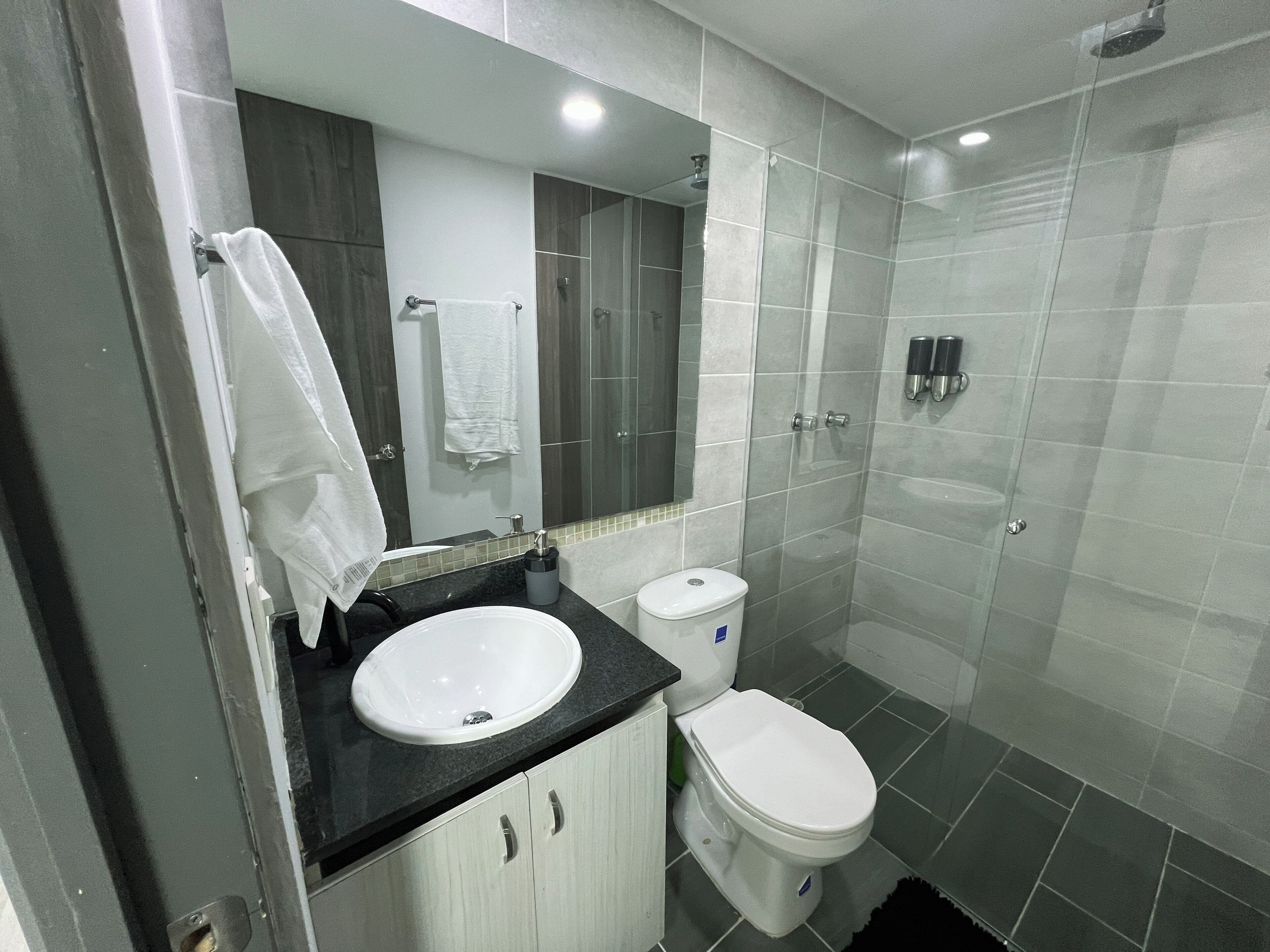 Un baño moderno con lavamanos, inodoro y ducha.
