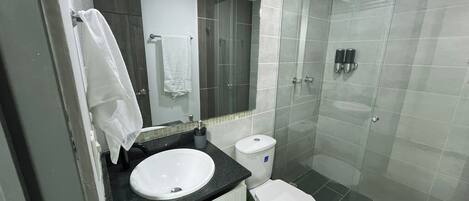 Un baño moderno con lavamanos, inodoro y ducha.