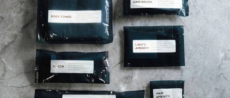 Six black packages labeled with different items: body towel, hair brush, lady's amenity, razor, tooth brush, and hair amenity.