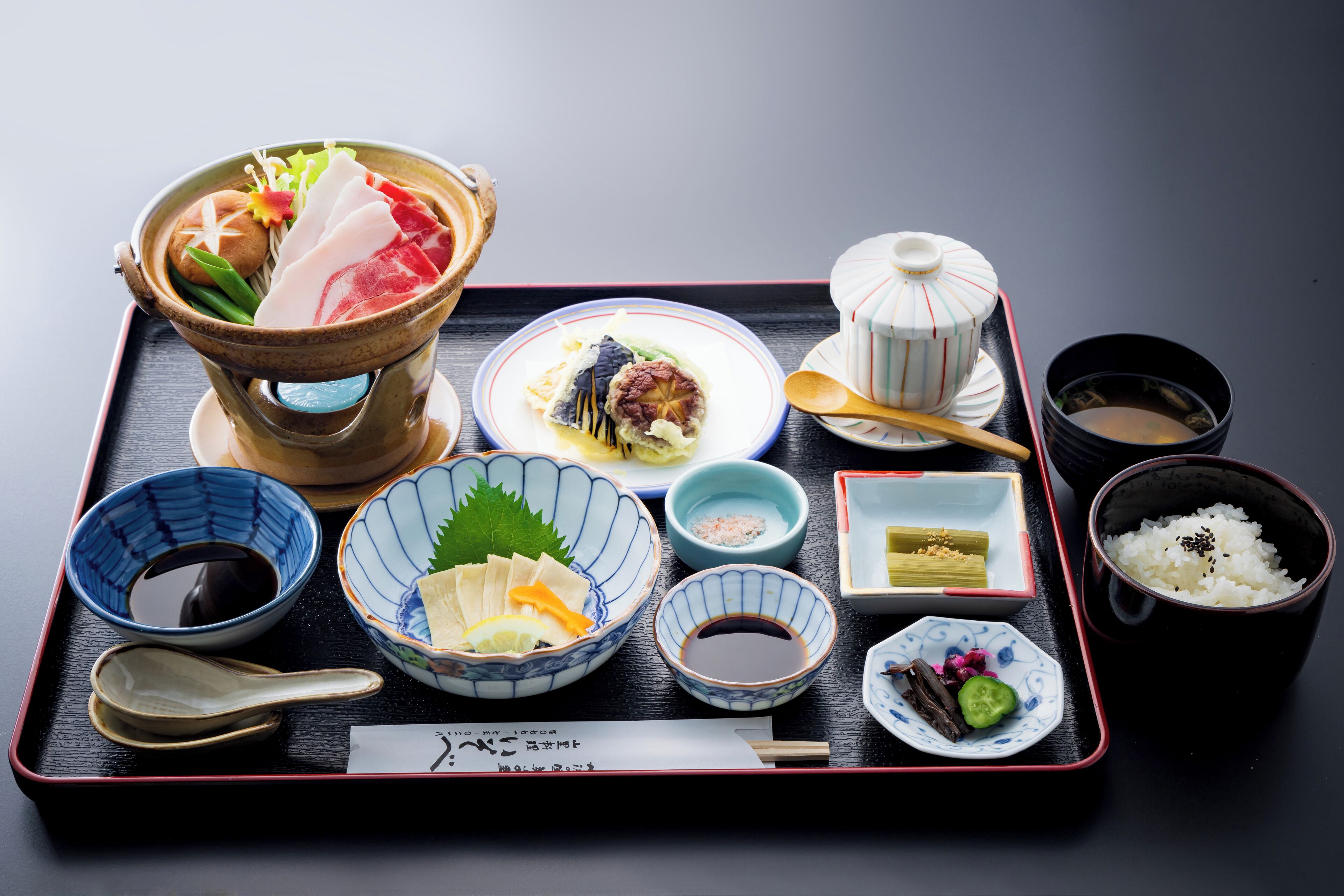 Ein Tablett mit verschiedenen japanischen Gerichten, darunter Sushi, Reis und Suppe.
