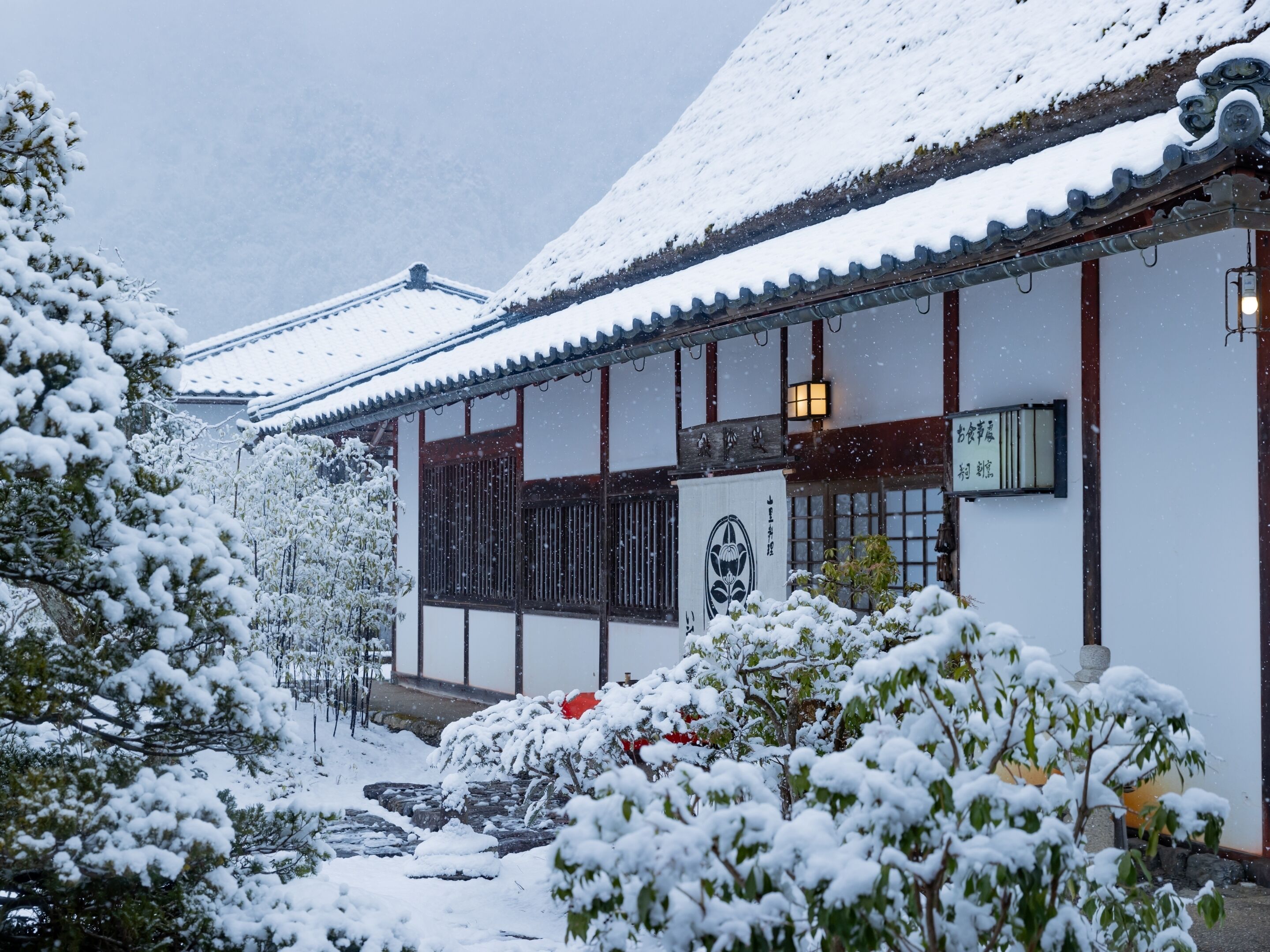 Ein traditionelles japanisches Gebäude mit verschneitem Dach und Holzwänden.