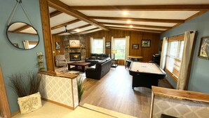 A spacious living area with a fireplace, seating, and a pool table. - The Horse Inn Around @ Spring Brook Resort (Wisconsin Dells)