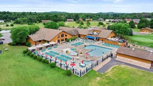 A lodge with a pool, outdoor seating, and a large lawn area. - The Horse Inn Around @ Spring Brook Resort (Wisconsin Dells)