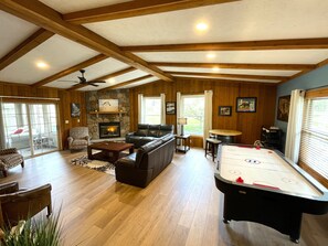 A spacious living room with a fireplace, leather sofas, a pool table, and a stone fireplace surround. - The Horse Inn Around @ Spring Brook Resort (Wisconsin Dells)