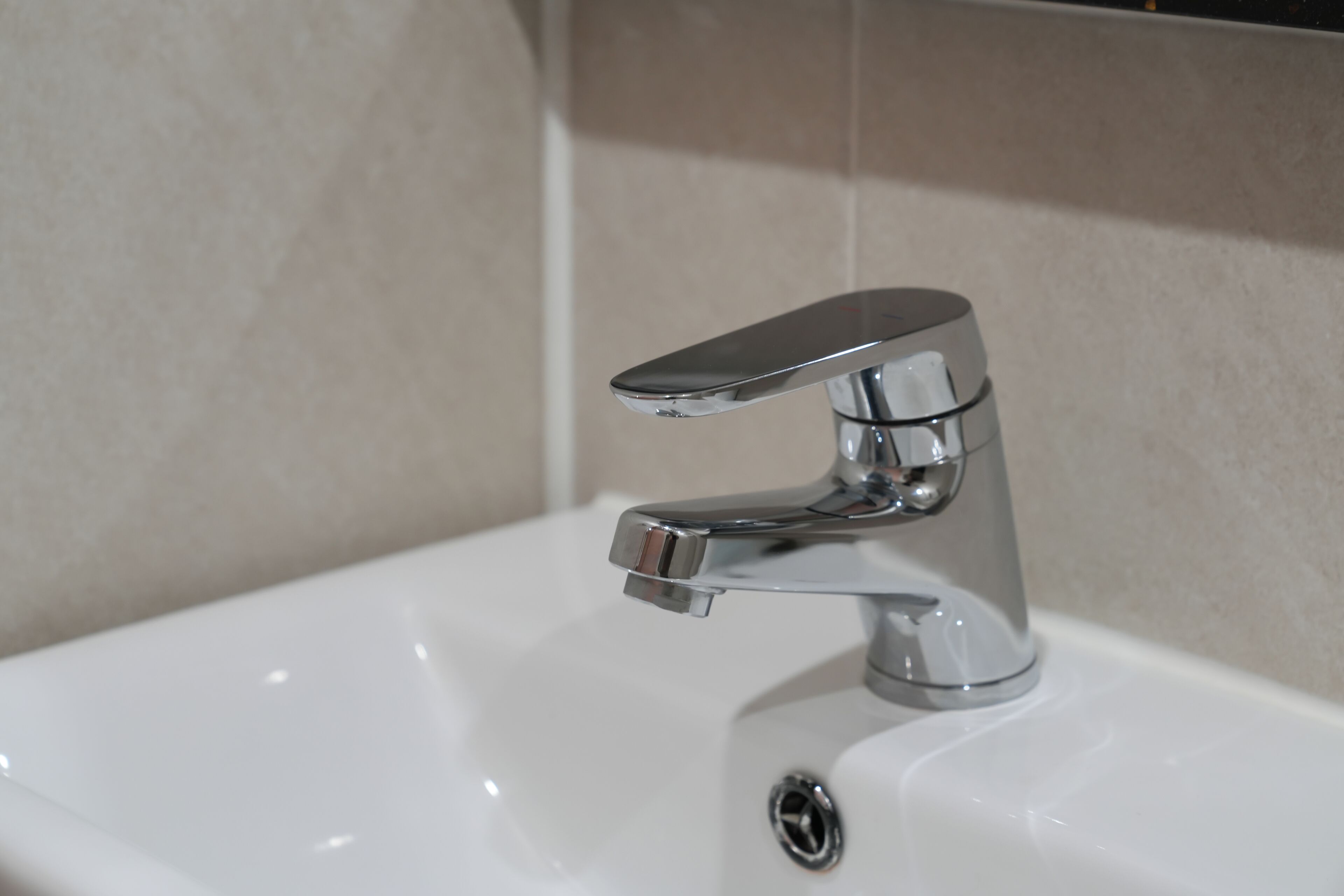 Ein Waschbecken mit chromfarbenem Wasserhahn und einem Einhebelgriff.