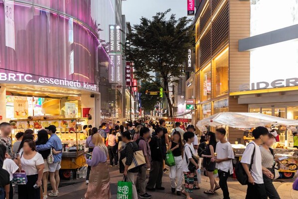 Une rue animée en milieu urbain, bordée de divers commerces et fréquentée par de nombreux piétons.