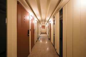 A hotel hallway with doors, light fixtures, and a tiled floor. - Hotel Cozy Ten (Seoul)