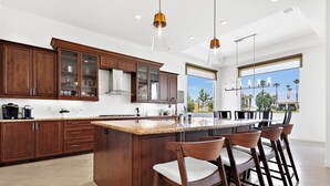 A modern kitchen with wooden cabinets, a large island, and bar stools.