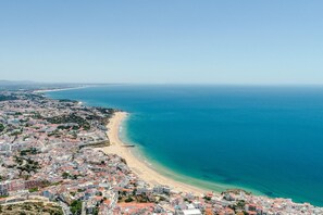 A coastal cityscape with a beach, buildings, and a clear blue sea.