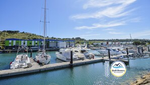 A marina with multiple boats docked, a green building with a blue roof, and a clear sky.