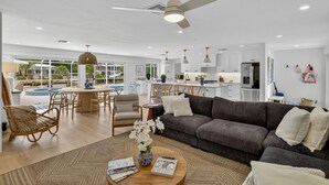 Ein großzügiger Wohnbereich mit grauem Sofa, einem Couchtisch mit Zeitschriften und einem Essbereich mit rundem Tisch.