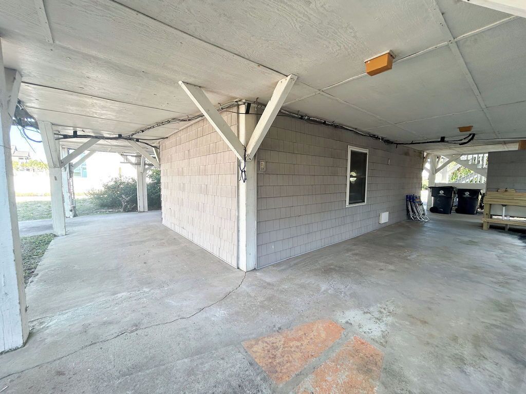 Un espace extérieur abrité, doté d’un sol en béton, d’un mur en briques et d’une porte.