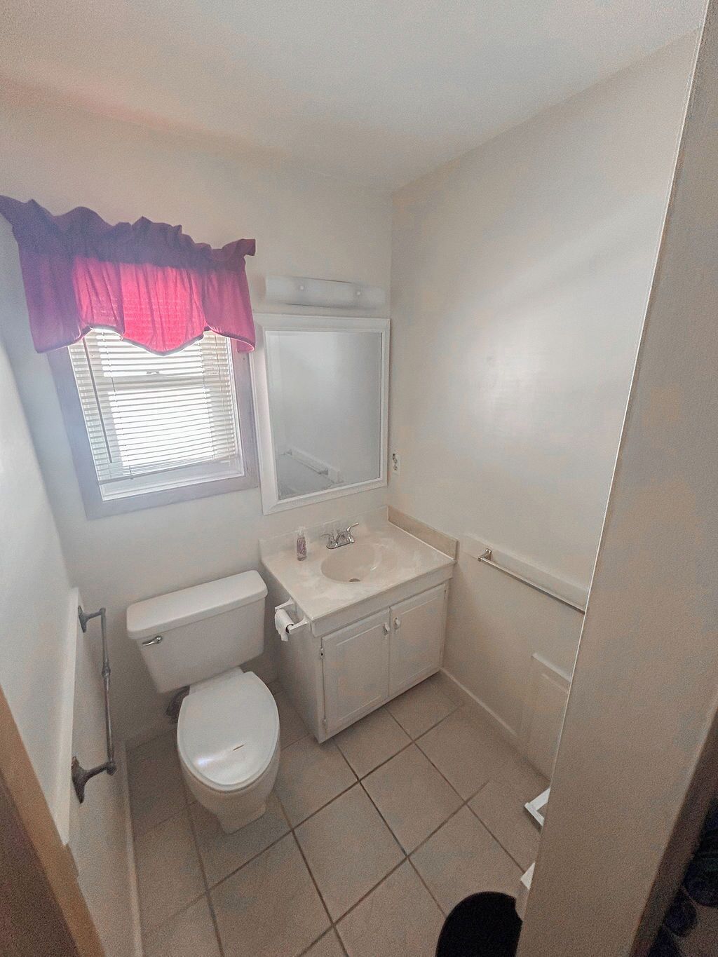 Une petite salle de bain propre, équipée de toilettes, d’un lavabo et d’un miroir.