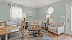 A living room with a wooden dining table, two sofas, a coffee table, and two lamps. - Endless Summer-Spacious 5BR Retreat Steps from Cherry Grove Beach! (North Myrtle Beach)