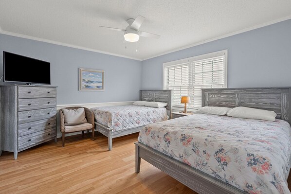 A bedroom with two beds, a dresser, a chair, a ceiling fan, and a TV. - Endless Summer-Spacious 5BR Retreat Steps from Cherry Grove Beach! (North Myrtle Beach)