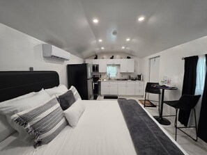 Ein kompaktes Hotelzimmer mit Bett, einer kleinen Küchenzeile und einem Essbereich.