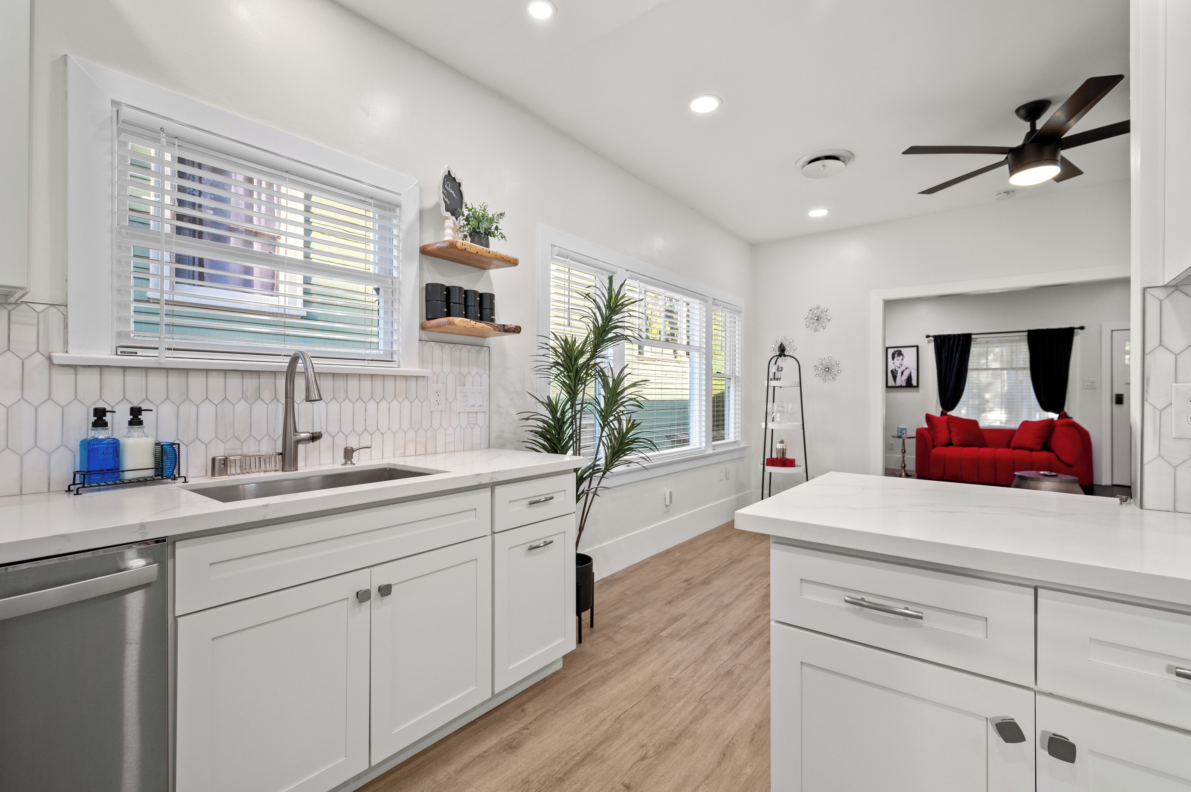 A modern kitchen with white cabinets, a sink, and a red sofa in the dining area.