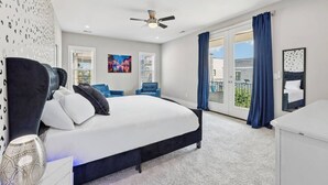 A modern hotel room with a large bed, a ceiling fan, a painting, a balcony with blue curtains, and a view of the city. - Friends in Skyline Places, 10 min to Broadway, Perfect for Groups! (Nashville)