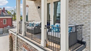 A two-story building with a brick exterior, a balcony with outdoor seating, and a stone foundation. - Friends in Skyline Places, 10 min to Broadway, Perfect for Groups! (Nashville)
