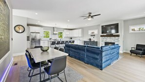 A modern kitchen with white cabinets, a central island, and a dining area with a table and chairs. - Friends in Skyline Places, 10 min to Broadway, Perfect for Groups! (Nashville)