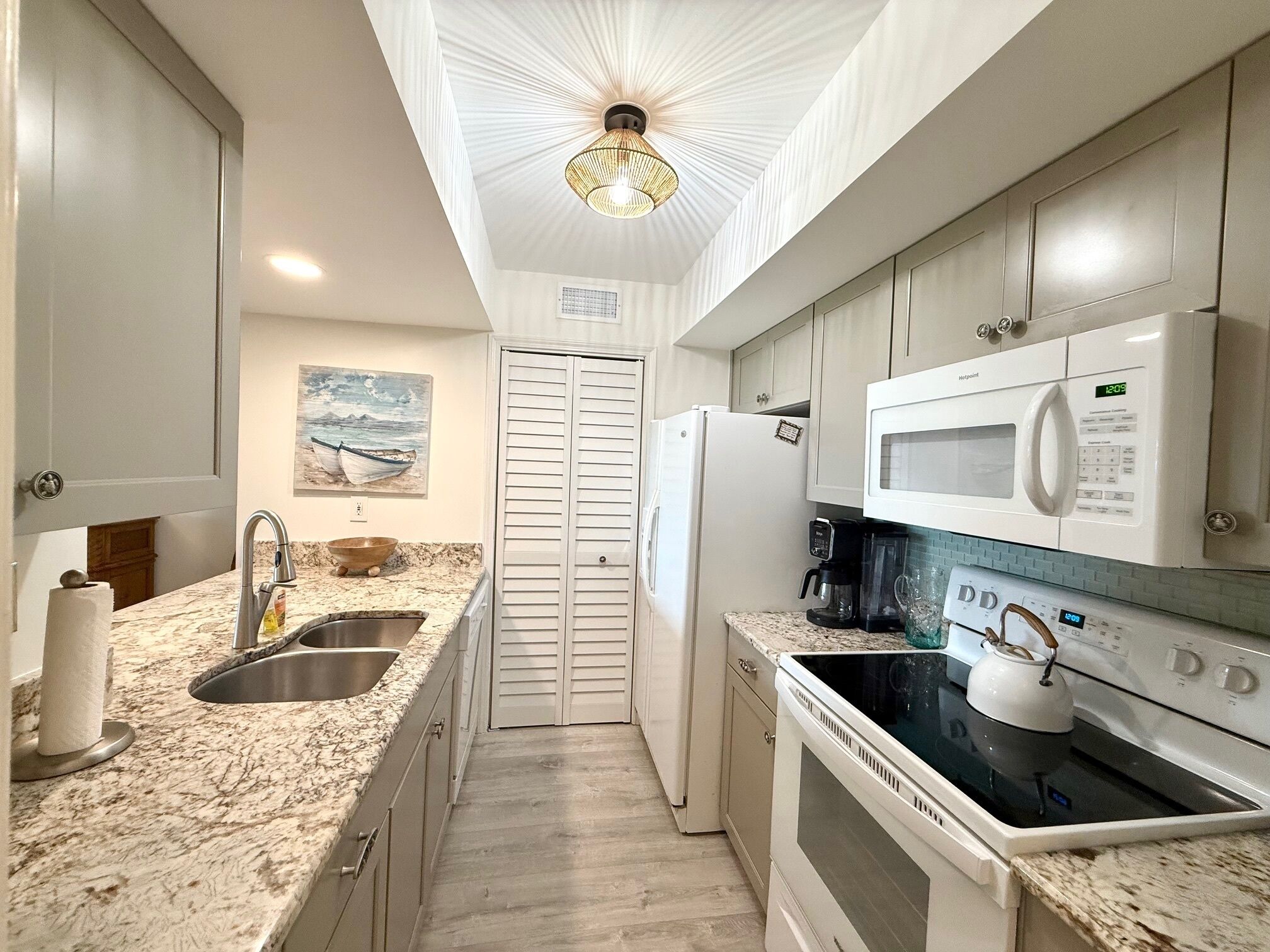 A modern kitchen with granite countertops, stainless steel appliances, and a unique ceiling light fixture.