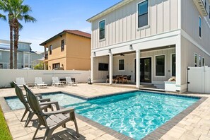 Ein modernes Haus mit Pool, Sitzgelegenheit im Freien und einer überdachten Terrasse.