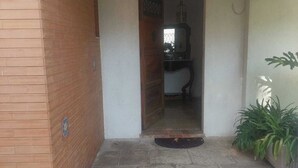 Una entrada con suelo de piedra, puerta de madera y planta en maceta.