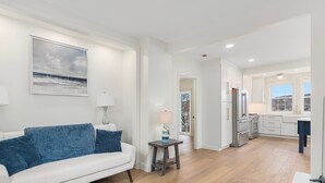 A modern living room with a white sofa, a small side table, and a painting on the wall.