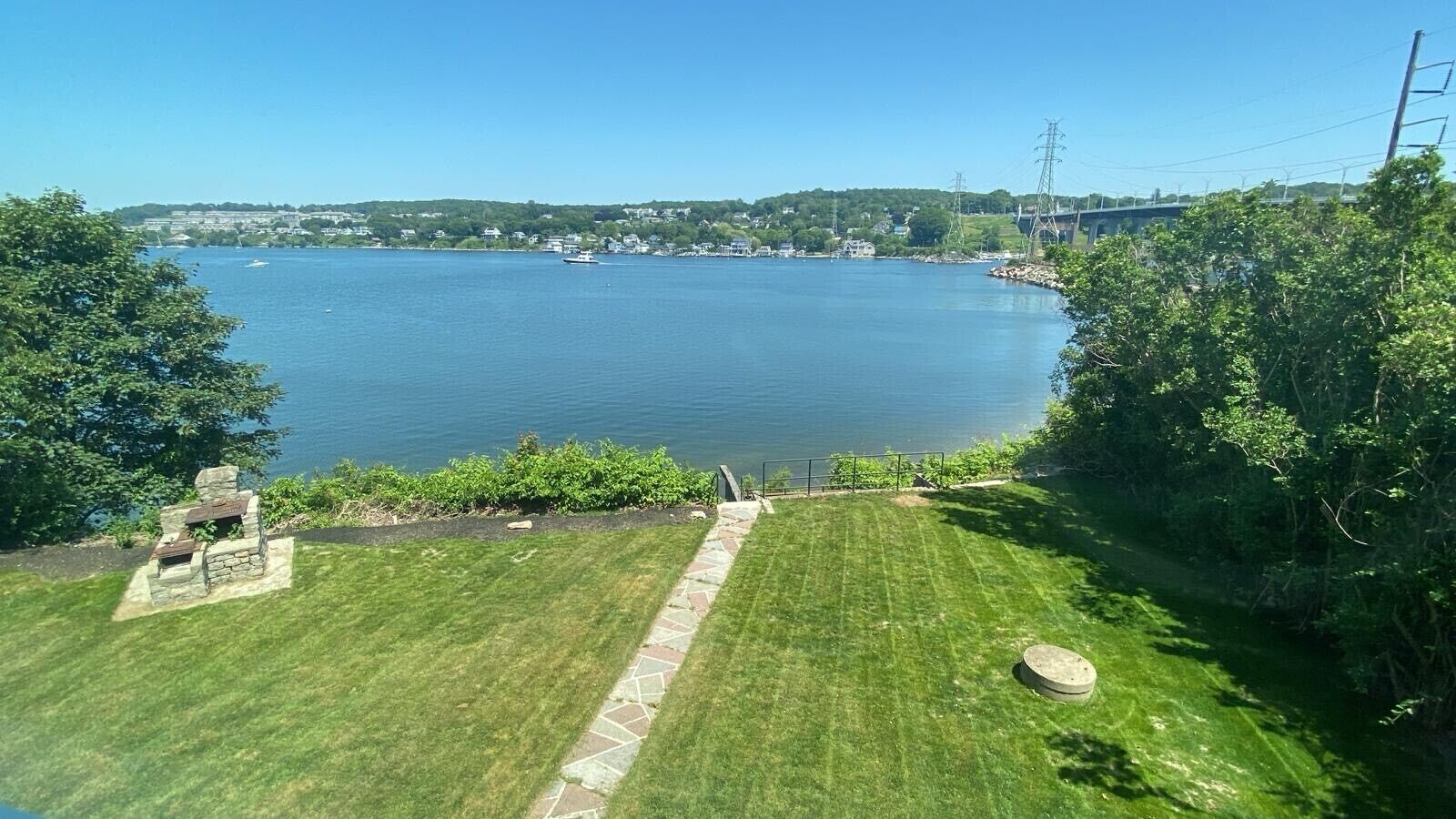 A view of a lake with a grassy area and a stone pathway leading to a dock.