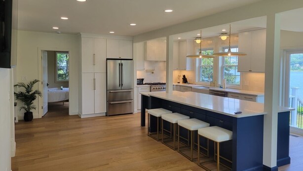 A modern kitchen with a central island, bar stools, and a large refrigerator.
