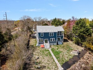 A two-story house with a front porch and a small garden area. - Luxury Waterfront House in Portsmouth, RI with Direct Beach Access (Portsmouth)