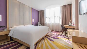 Una habitación de hotel con una cama grande, un escritorio, una silla y un televisor.