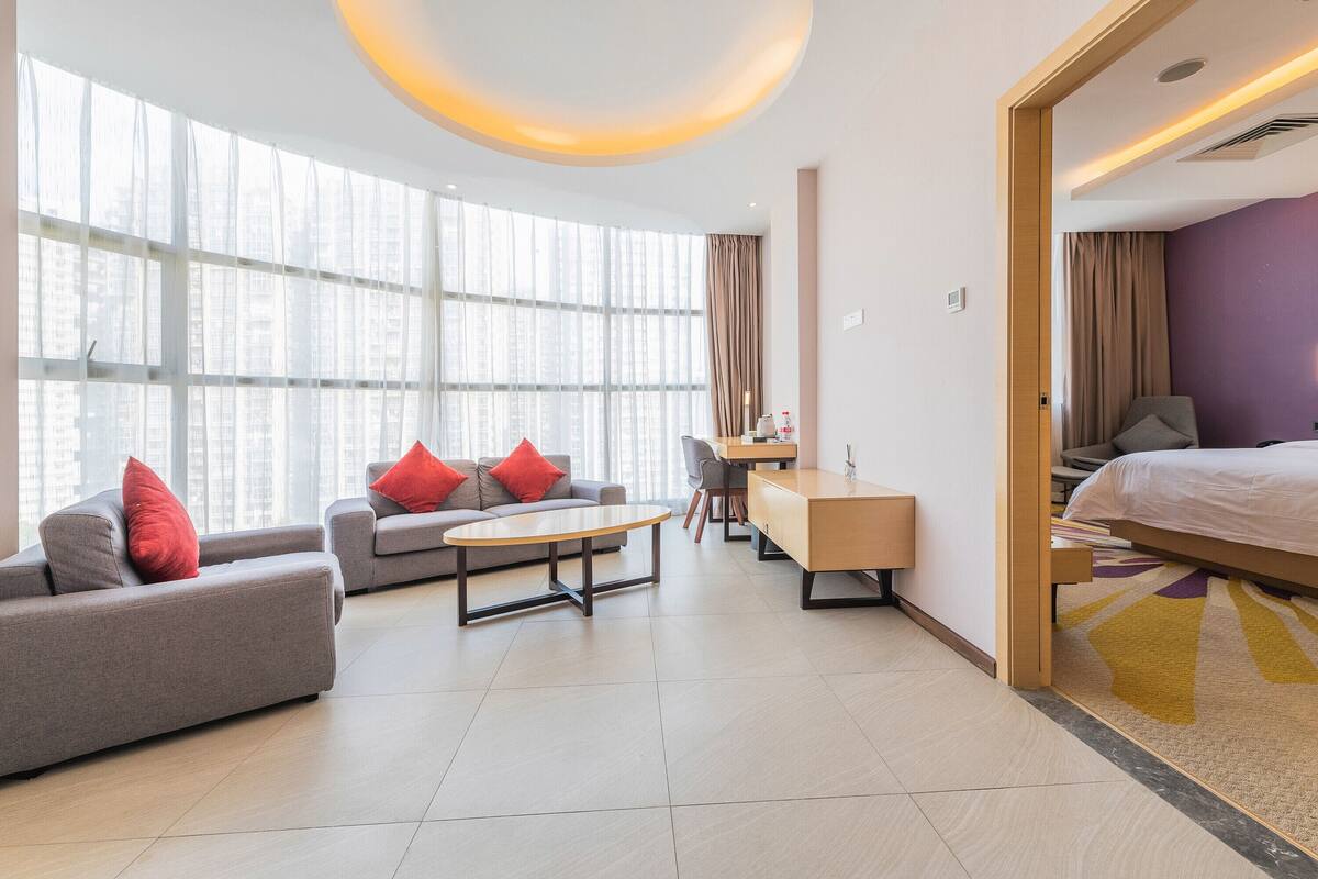 A modern hotel room with a sofa, a desk, and a bed.
