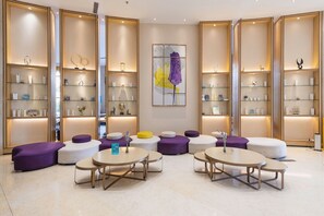 Una hall moderna con zone relax, un'opera d'arte al centro e scaffali con diversi oggetti.