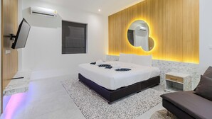Ein modernes Schlafzimmer mit einem großen Bett, einem an der Wand montierten Fernseher und einer Wand mit Holzvertäfelung und einem runden Spiegel.