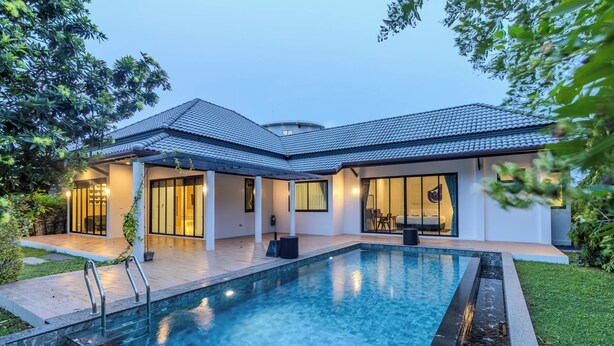 Ein modernes Haus mit Schwimmbad, großen Fenstern und einem gepflegten Rasen.