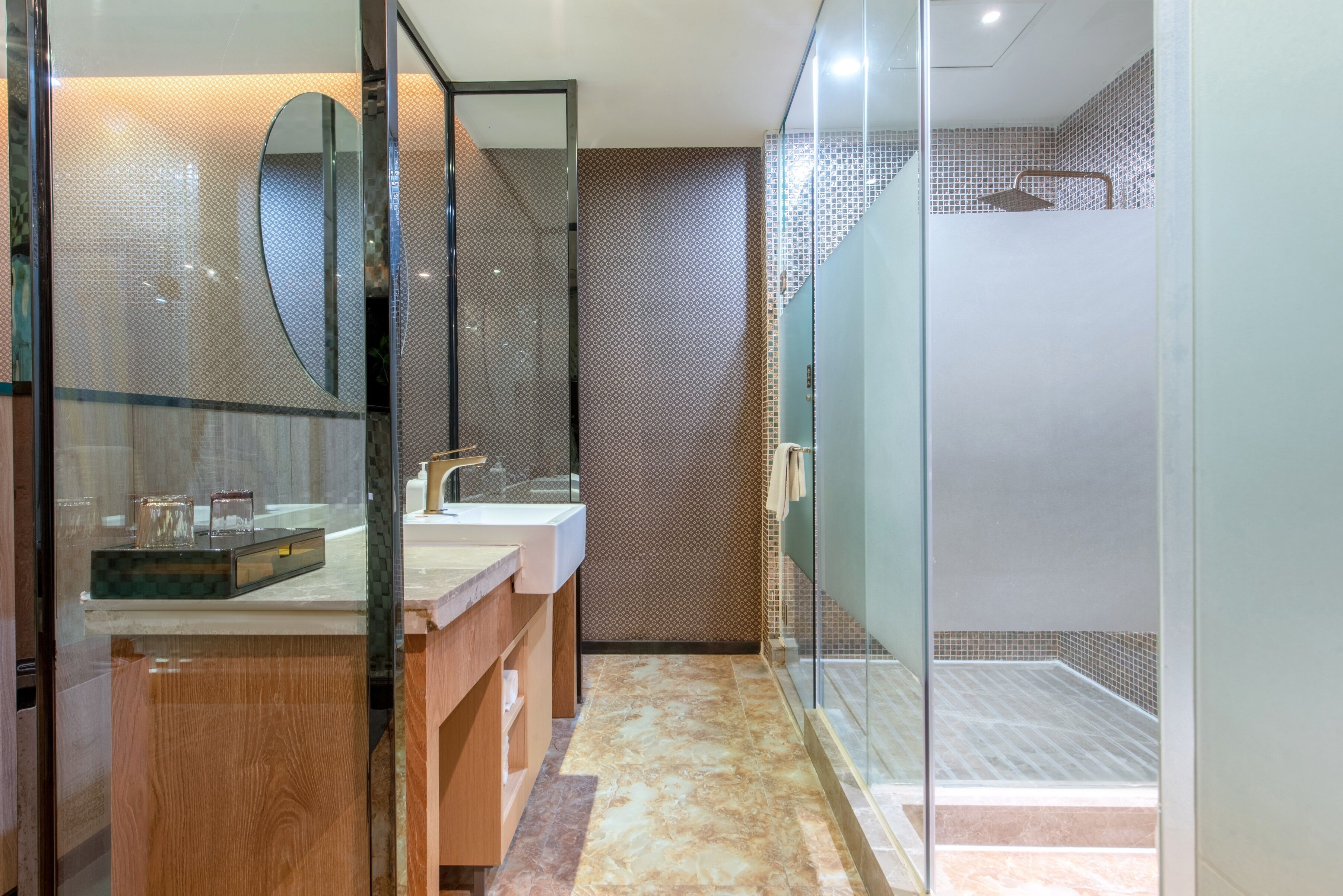 Un baño moderno con cabina de ducha de vidrio, tocador de madera y un espejo grande.