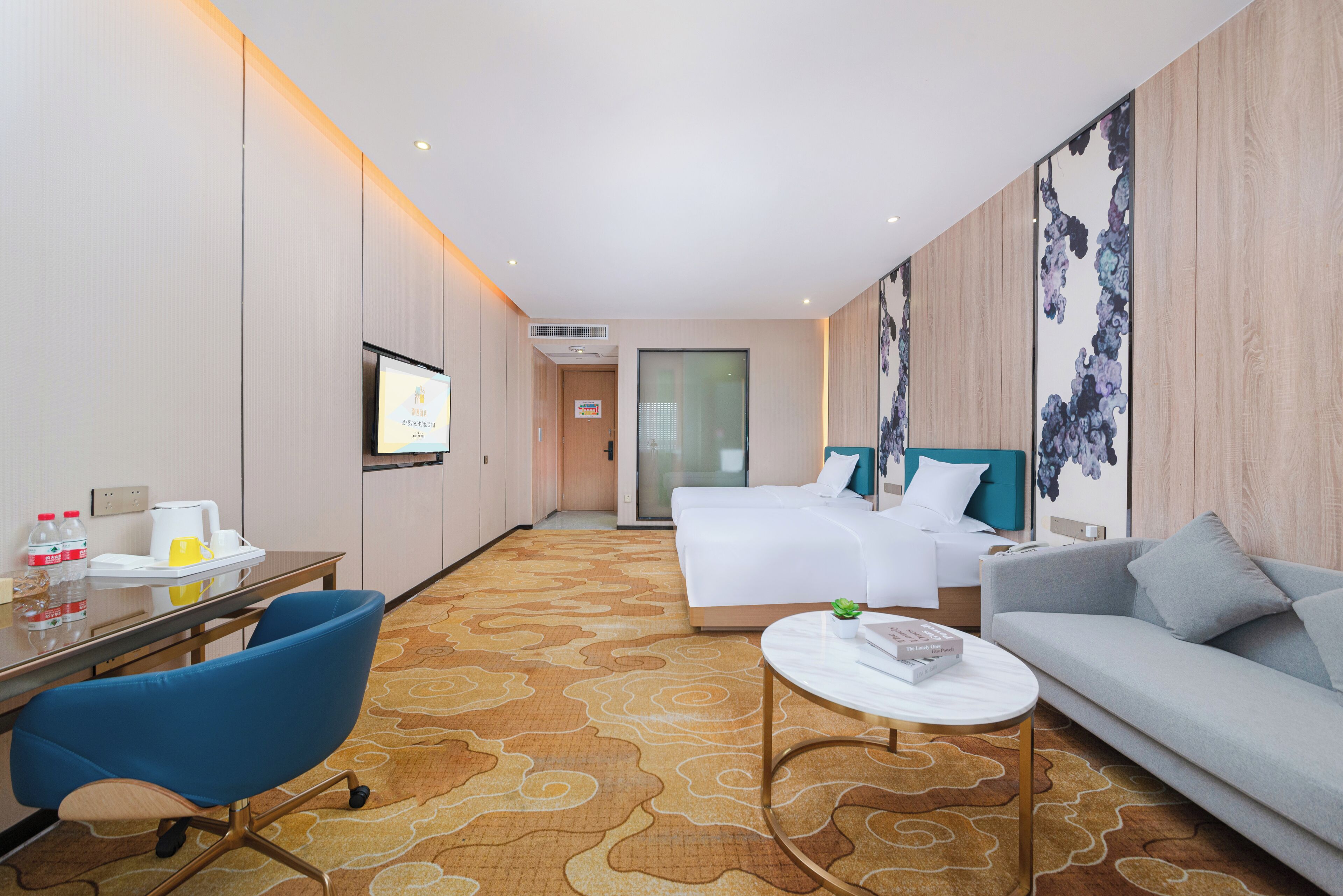 A hotel room with a bed, a sofa, a desk with a chair, a TV, and a small table.
